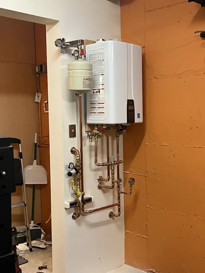 Plumbing technician inspecting water heater connections in Stayton